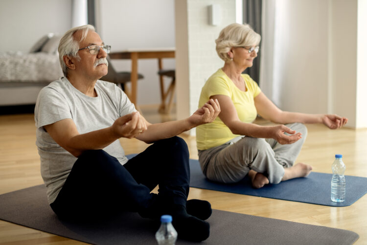 Senior man and his wife practicing Yoga while working out together at home.